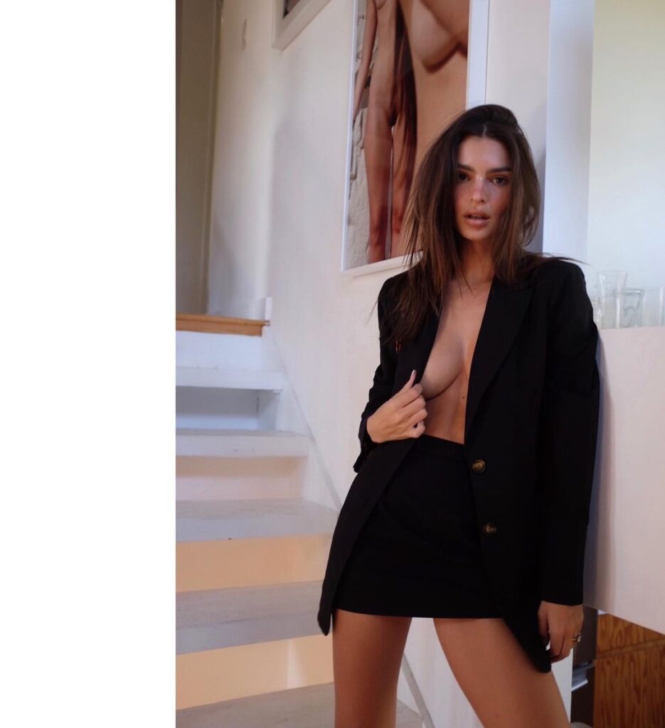 Эмили Ратаковски в черном костюме эротично обнажает грудь